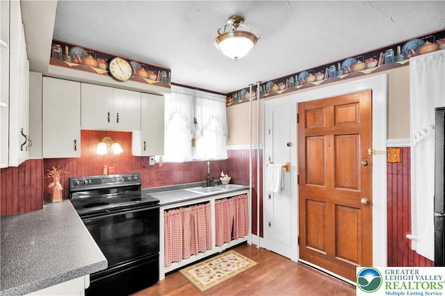 600 S Hoffert St, Fountain Hill Boro, PA 18015 - kitchen with black / electric stove, white cabinetry, light wood-style flooring, a wainscoted wall, and wooden walls