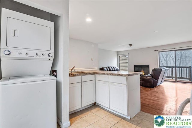 417 Hickory Dr, Jackson Twp, PA 18372 - kitchen featuring estacked washer and dryer, a peninsula, open floor plan, white cabinets, and light tile patterned flooring