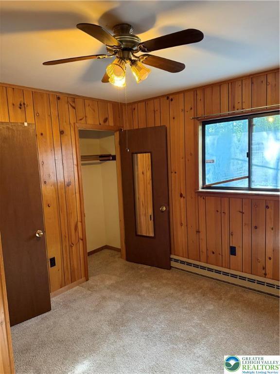 9817 Deerwood Dr, Coolbaugh Twp, PA 18466 - unfurnished bedroom featuring a baseboard heating unit, wood walls, a closet, and light colored carpet