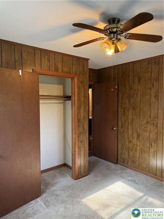 9817 Deerwood Dr, Coolbaugh Twp, PA 18466 - unfurnished bedroom with carpet floors, a closet, a ceiling fan, and wood walls