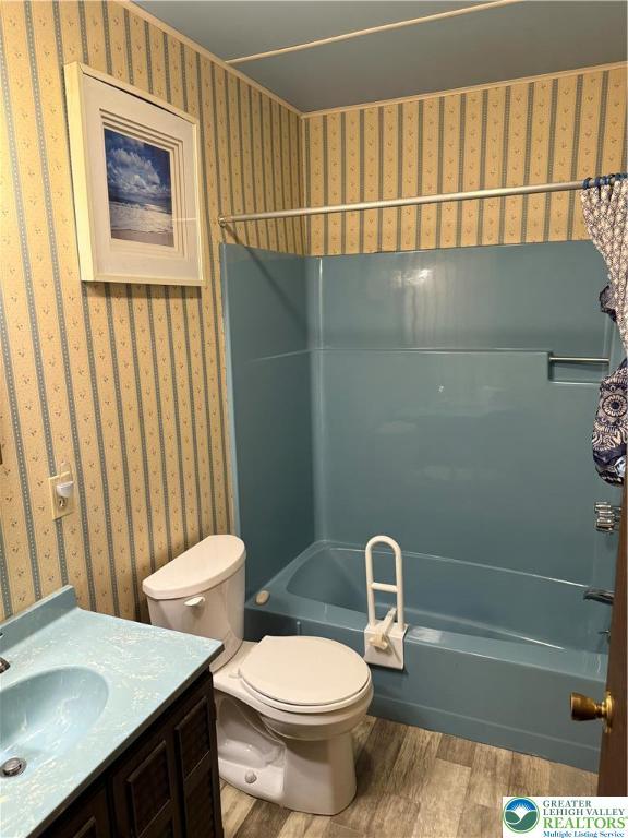 9817 Deerwood Dr, Coolbaugh Twp, PA 18466 - bathroom featuring wood finished floors, wallpapered walls, shower / tub combination, and vanity