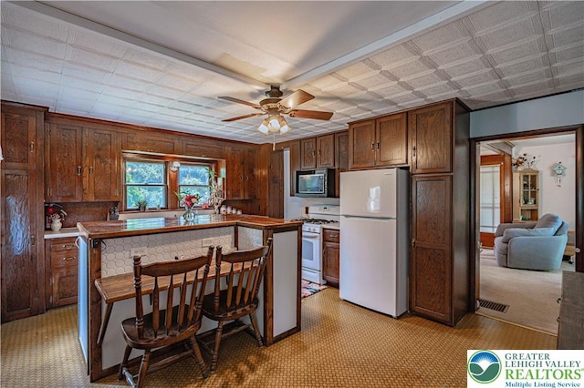 636 School Rd, Plainfield Twp, PA 18064 - kitchen featuring white appliances, a ceiling fan, wood walls, and a center island