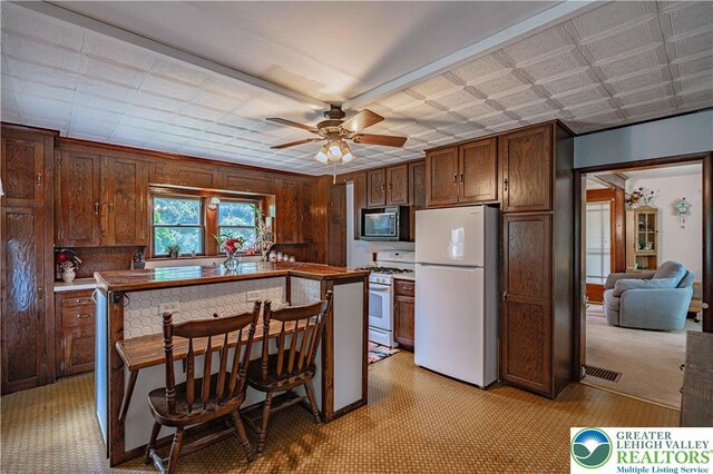 636 School Rd, Plainfield Twp, PA 18064 - kitchen with white appliances, a ceiling fan, wood walls, and a center island