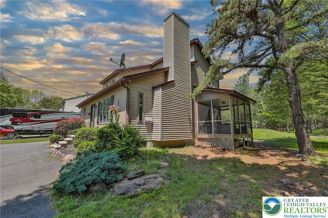 179 Chippewa Trl, Penn Forest Twp, PA 18210 - property exterior at dusk with a sunroom and a chimney