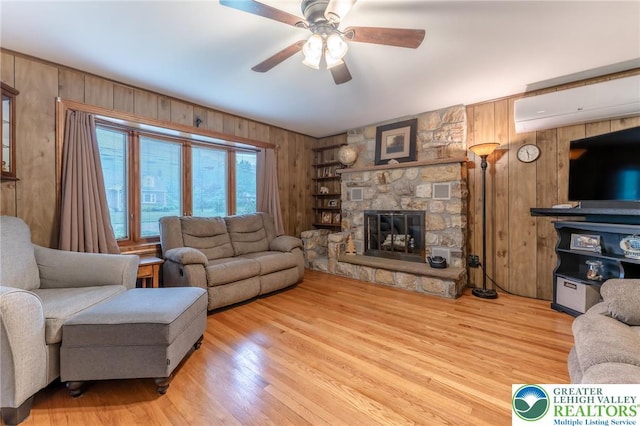1571 Penn Dr, West Penn Twp, PA 18211 - living area with wooden walls, a wall unit AC, ceiling fan, a stone fireplace, and wood finished floors