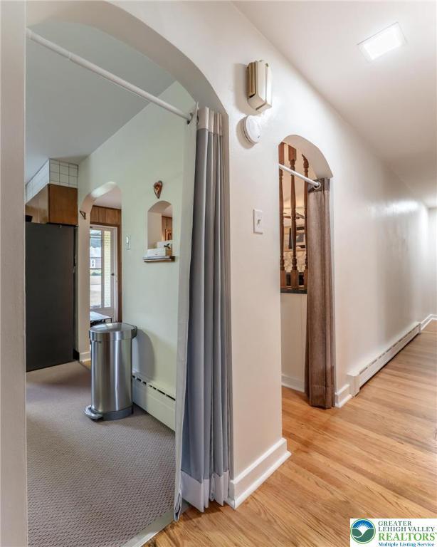 1571 Penn Dr, West Penn Twp, PA 18211 - hall with arched walkways, a baseboard heating unit, and light wood-style floors