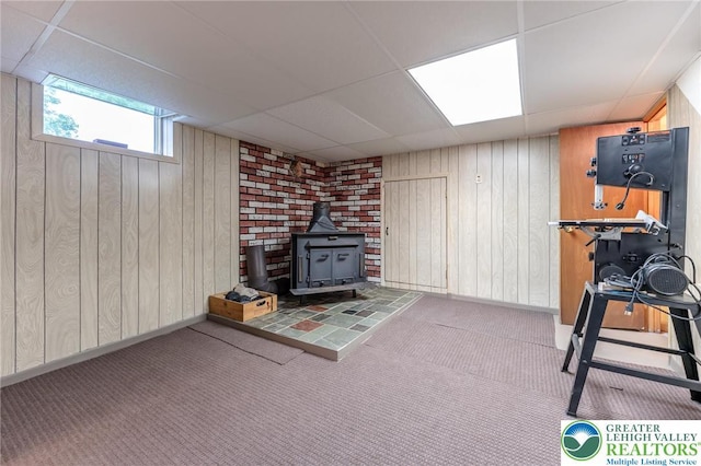 1571 Penn Dr, West Penn Twp, PA 18211 - exercise area featuring a paneled ceiling, a wood stove, wood walls, and carpet floors