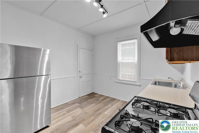 834 Bushkill St, Easton, PA 18042 - kitchen with freestanding refrigerator, range hood, light wood-style flooring, light countertops, and a wainscoted wall