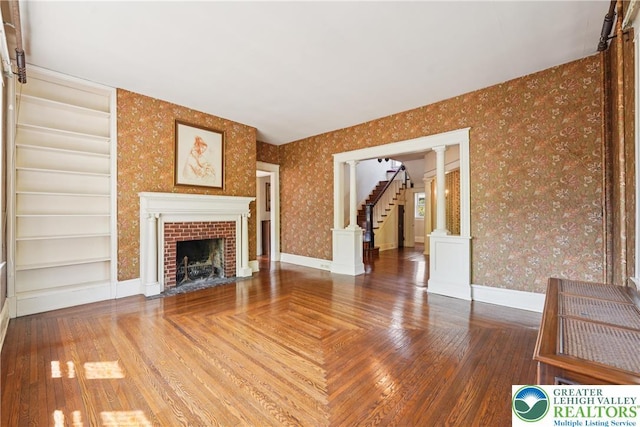 200 W Pierce St, Easton, PA 18042 - unfurnished living room featuring wallpapered walls, stairs, a brick fireplace, built in features, and parquet floors