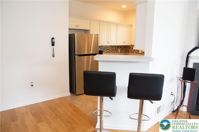 607 Prestwick Dr, Williams Twp, PA 18042 - kitchen featuring freestanding refrigerator, decorative backsplash, light countertops, a peninsula, and a kitchen bar