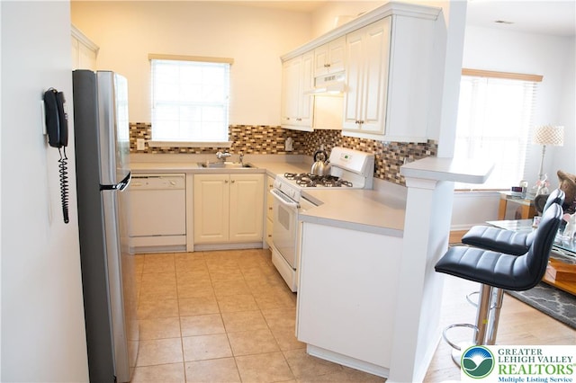 607 Prestwick Dr, Williams Twp, PA 18042 - kitchen with white appliances, under cabinet range hood, a breakfast bar, and healthy amount of natural light