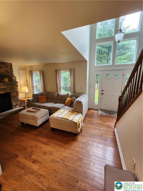 7 Twelve Oaks Trl, Chestnuthill Twp, PA 18353 - living room with wood-type flooring, a stone fireplace, a high ceiling, and stairway