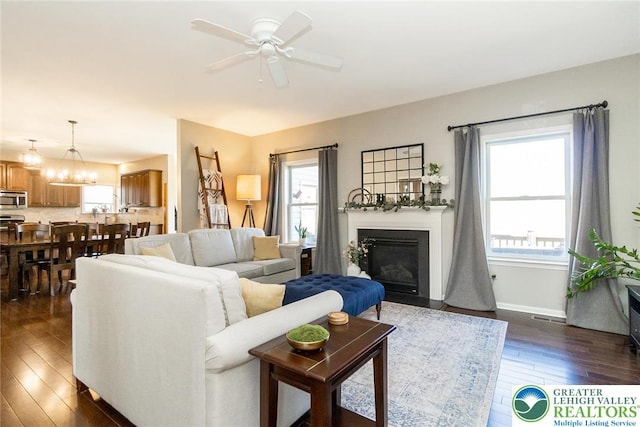 21 Millbrook Ct, Palmer Twp, PA 18045 - living area with dark wood-type flooring, ceiling fan, a fireplace with flush hearth, and a chandelier