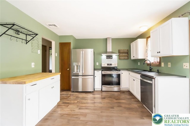 2227 Cheyenne Dr, Tunkhannock Township, PA 18610 - kitchen featuring appliances with stainless steel finishes, wall chimney exhaust hood, white cabinets, light wood-type flooring, and butcher block counters