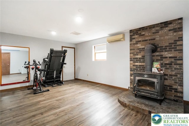 2227 Cheyenne Dr, Tunkhannock Township, PA 18610 - exercise area featuring a wall mounted air conditioner, wood finished floors, and a wood stove