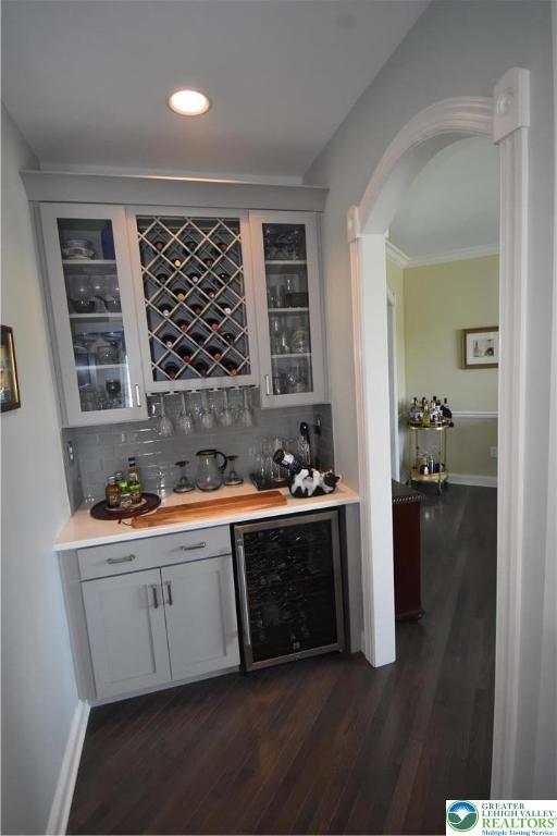 4323 Saratoga Dr, Lower Nazareth Twp, PA 18020 - indoor dry bar featuring beverage cooler, dark wood finished floors, backsplash, recessed lighting, and arched walkways