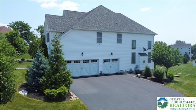 4323 Saratoga Dr, Lower Nazareth Twp, PA 18020 - view of side of property with a garage, driveway, a shingled roof, and a lawn
