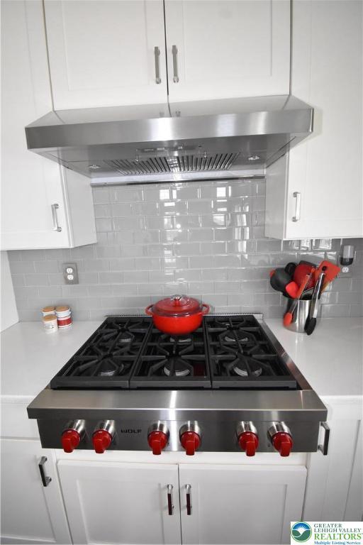 4323 Saratoga Dr, Lower Nazareth Twp, PA 18020 - kitchen featuring stainless steel gas cooktop, white cabinets, decorative backsplash, extractor fan, and light countertops