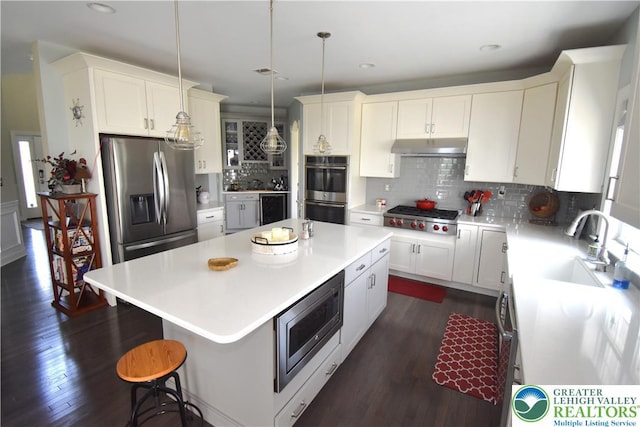 4323 Saratoga Dr, Lower Nazareth Twp, PA 18020 - kitchen featuring stainless steel appliances, a kitchen island, under cabinet range hood, backsplash, and dark wood-style flooring