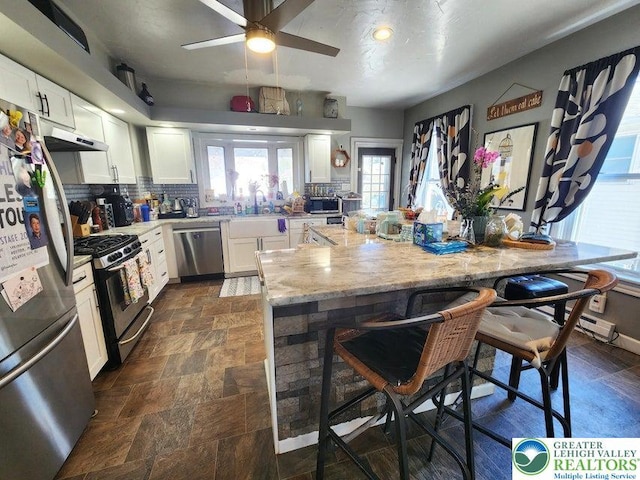 14 W 10th St, Jim Thorpe Borough, PA 18229 - kitchen featuring stainless steel appliances, a breakfast bar area, white cabinetry, dark stone finish floors, and light stone counters