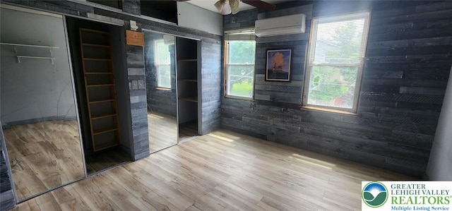 2463 Hillside Ave, Wilson Boro, PA 18042 - empty room featuring a wall unit AC, wood walls, wood finished floors, a ceiling fan, and healthy amount of natural light