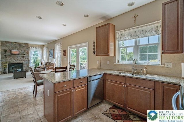 3213 Overlook Dr, Lower Macungie Twp, PA 18049 - kitchen featuring stainless steel dishwasher, light stone counters, a peninsula, a stone fireplace, and brown cabinetry