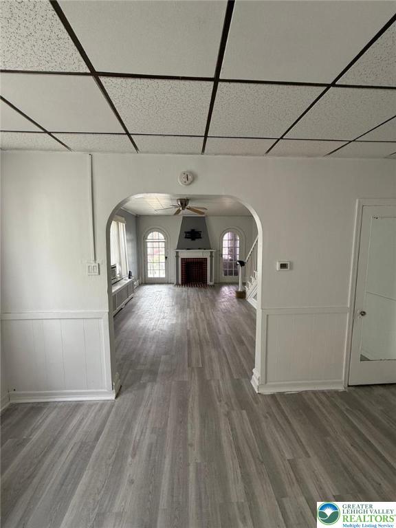 314 S Saint Cloud St, Allentown City, PA 18104 - unfurnished living room featuring a drop ceiling, arched walkways, wood finished floors, a ceiling fan, and wainscoting