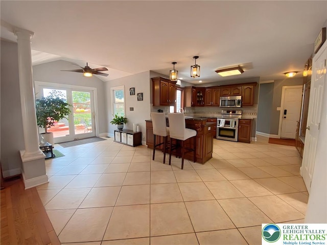 5545 Roberts Rd, North Whitehall Twp, PA 18078 - kitchen featuring appliances with stainless steel finishes, ornate columns, a peninsula, glass insert cabinets, and a breakfast bar area
