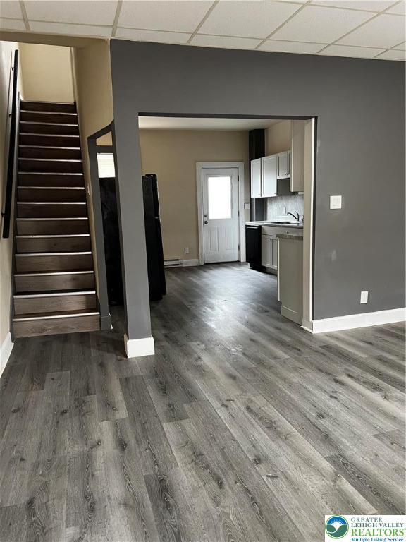 142 Front St, Catasauqua Boro, PA 18032 - unfurnished living room with dark wood-style floors, a drop ceiling, stairway, and a baseboard heating unit