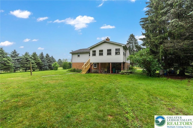2560 Community Dr, Moore Twp, PA 18014 - rear view of property with brick siding, a chimney, a lawn, and stairway