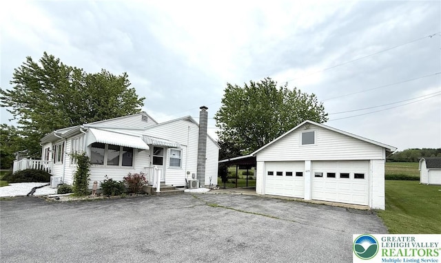 619 Penn Dr, West Penn Twp, PA 18252 - view of front facade featuring an outdoor structure, a detached garage, a chimney, and a front lawn