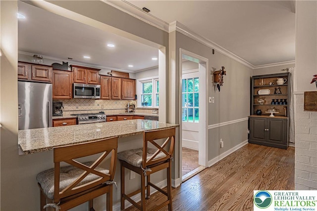 326 N Main St, Allentown City, PA 18104 - kitchen with stainless steel appliances, wood finished floors, a kitchen breakfast bar, light stone countertops, and ornamental molding
