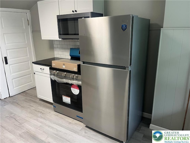 827 Louis St, Easton, PA 18042 - kitchen with stainless steel appliances, light wood-type flooring, white cabinets, tasteful backsplash, and dark countertops