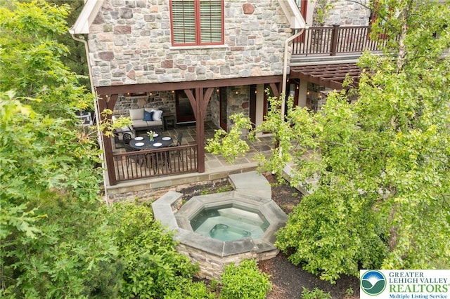 3054 Jordan Rd, North Whitehall Twp, PA 18069 - rear view of house with stone siding, an in-ground hot tub, a patio area, and a deck