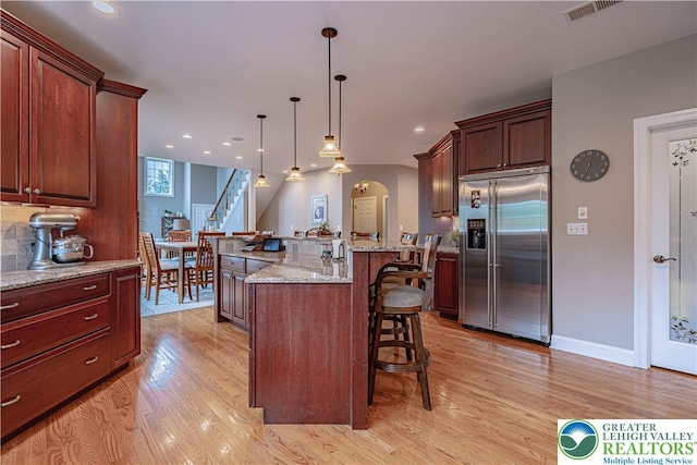 6532 Forest Knoll Ct, Upper Macungie Twp, PA 18106 - kitchen with built in refrigerator, a kitchen breakfast bar, light wood-style floors, arched walkways, and pendant lighting