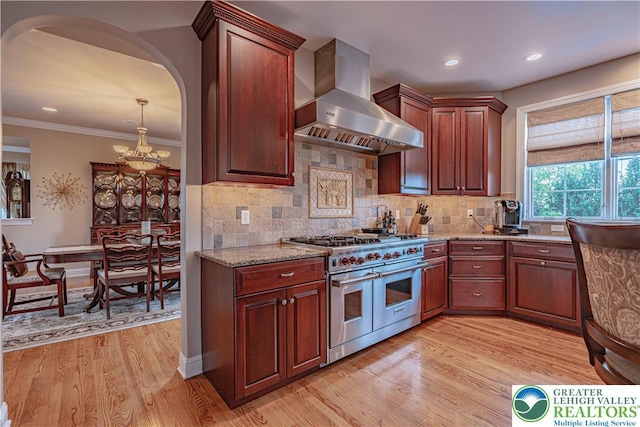 6532 Forest Knoll Ct, Upper Macungie Twp, PA 18106 - kitchen with wall chimney range hood, double oven range, light wood-style floors, arched walkways, and recessed lighting