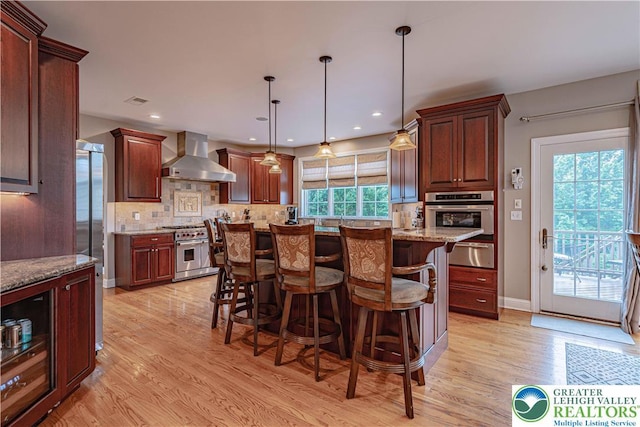 6532 Forest Knoll Ct, Upper Macungie Twp, PA 18106 - kitchen with high end appliances, wall chimney exhaust hood, a warming drawer, decorative backsplash, and light wood finished floors