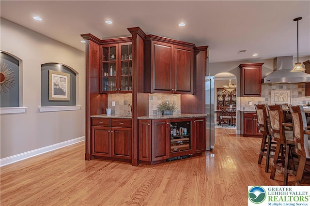 6532 Forest Knoll Ct, Upper Macungie Twp, PA 18106 - indoor bar with wall chimney range hood, arched walkways, light wood-style flooring, stainless steel fridge, and recessed lighting