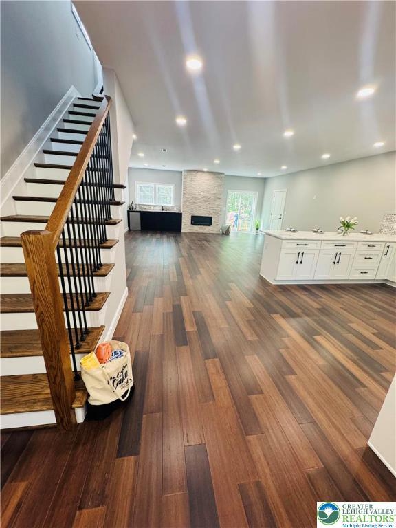 211 Maxatawny Dr, Coolbaugh Twp, PA 18347 - living room featuring stairs, dark wood-style flooring, a stone fireplace, and recessed lighting