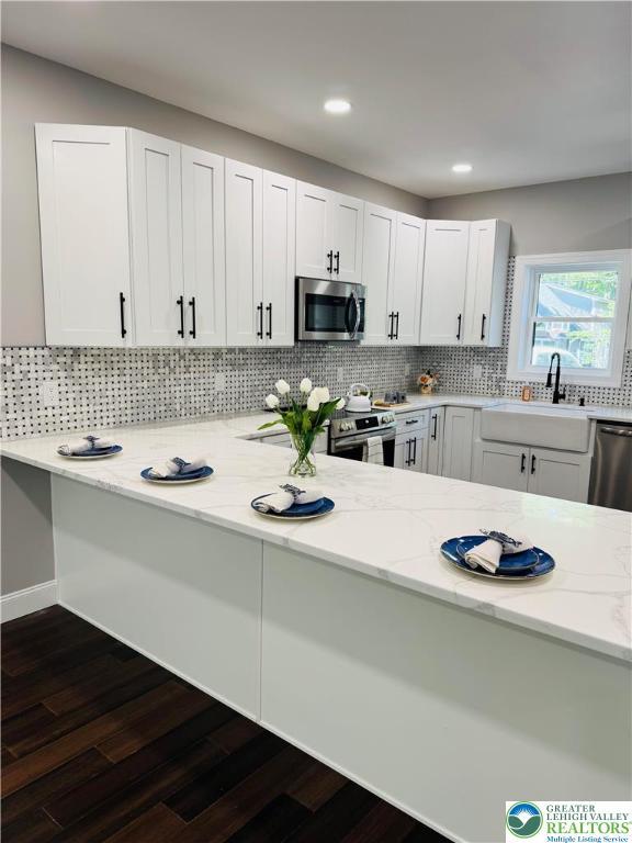 211 Maxatawny Dr, Coolbaugh Twp, PA 18347 - kitchen with stainless steel appliances, light stone counters, dark wood finished floors, tasteful backsplash, and recessed lighting