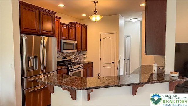 102 Gray Dr, Allen Twp, PA 18067 - kitchen with stainless steel appliances, a peninsula, tasteful backsplash, a kitchen breakfast bar, and decorative light fixtures