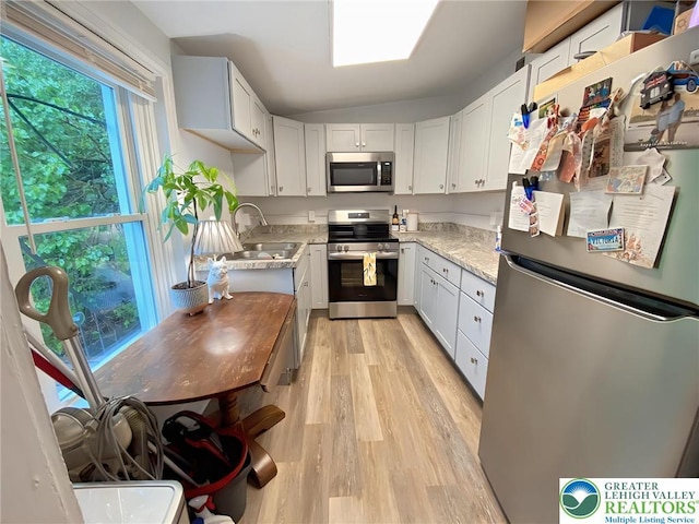 209 Northampton St, Easton, PA 18042 - kitchen featuring appliances with stainless steel finishes, light wood-type flooring, white cabinetry, and vaulted ceiling