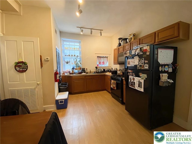 209 Northampton St, Easton, PA 18042 - kitchen with black appliances, light wood-type flooring, and brown cabinets