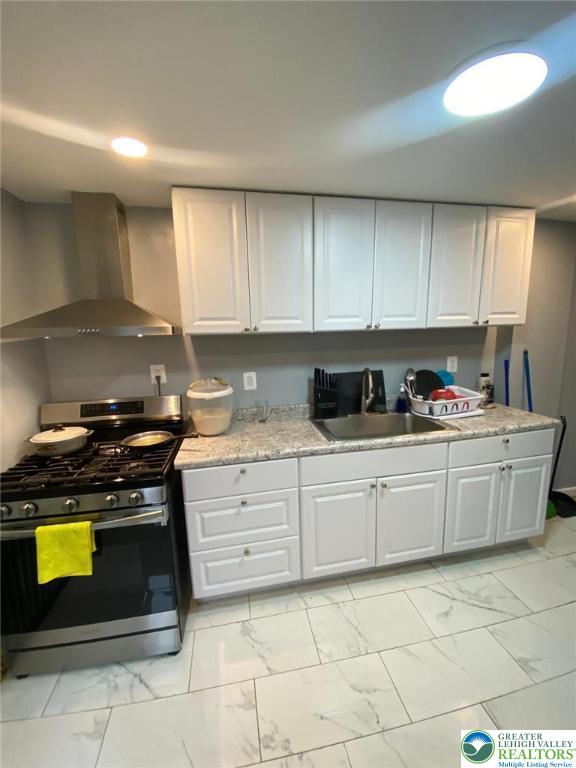 522 N Jordan St, Allentown City, PA 18102 - kitchen with stainless steel gas range, wall chimney range hood, light marble finish floors, white cabinets, and recessed lighting
