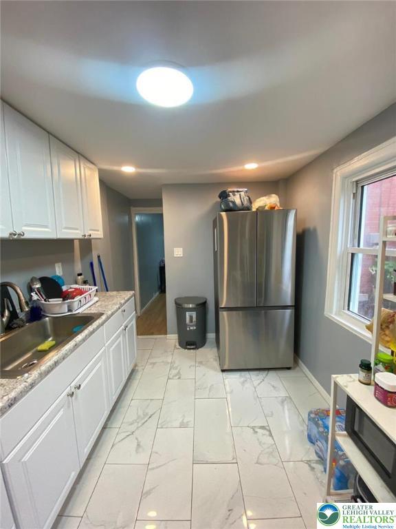 522 N Jordan St, Allentown City, PA 18102 - kitchen with freestanding refrigerator, white cabinets, and light marble finish flooring