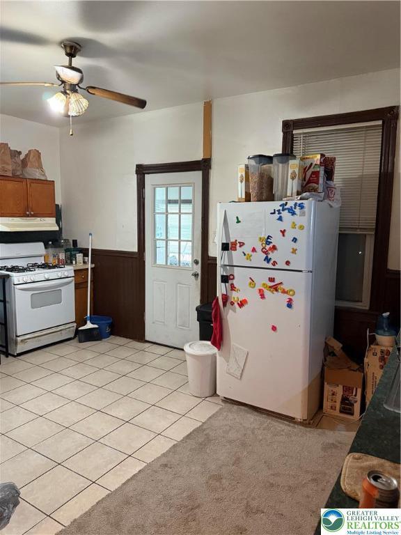 713 E 5th St, Bethlehem City, PA 18015 - kitchen with white appliances, a wainscoted wall, under cabinet range hood, light tile patterned floors, and ceiling fan