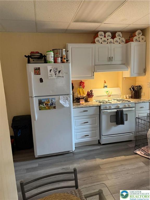 713 E 5th St, Bethlehem City, PA 18015 - kitchen featuring white appliances, a drop ceiling, under cabinet range hood, dark wood-style floors, and white cabinets