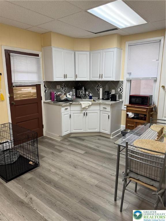 713 E 5th St, Bethlehem City, PA 18015 - kitchen with white cabinetry, light wood-style floors, decorative backsplash, and light stone countertops