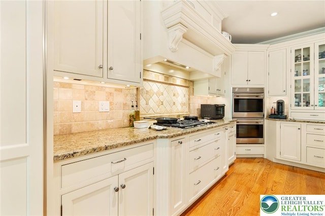 2051 Forge Run, Bethlehem City, PA 18015 - kitchen with appliances with stainless steel finishes, tasteful backsplash, glass insert cabinets, and light wood-type flooring