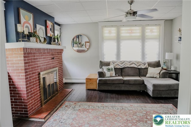 5242 3rd St, Whitehall Twp, PA 18052 - living room with a paneled ceiling, dark wood-style floors, a ceiling fan, a brick fireplace, and a baseboard radiator